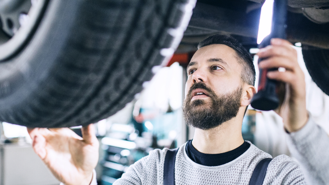 Delphi Technologies Expert standing underneath a vehicle, inspecting the wheel.