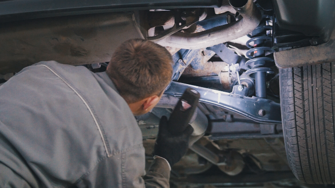 Delphi Technologies Expert using a torch to investigate the suspension of a car.