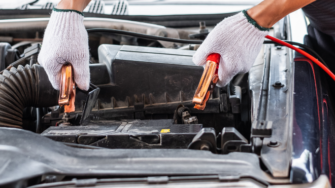 Delphi Expert attaching jumper cables to a car battery.