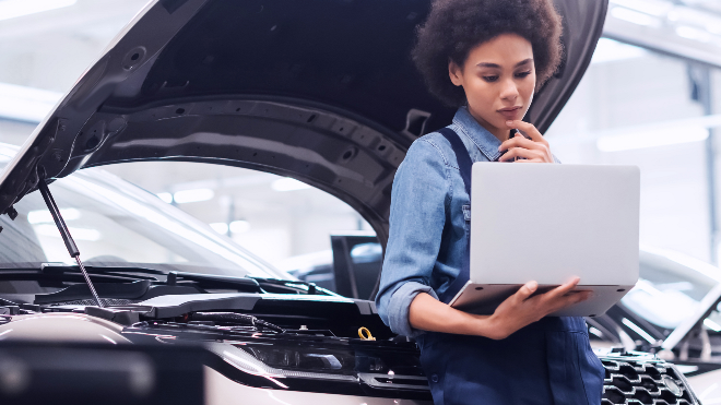 Delphi Expert sitting on a car bumper using a laptop.