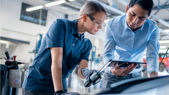 Delphi Technologies Experts using a tablet and an inspection lamp to investigate under the bonnet of a car.